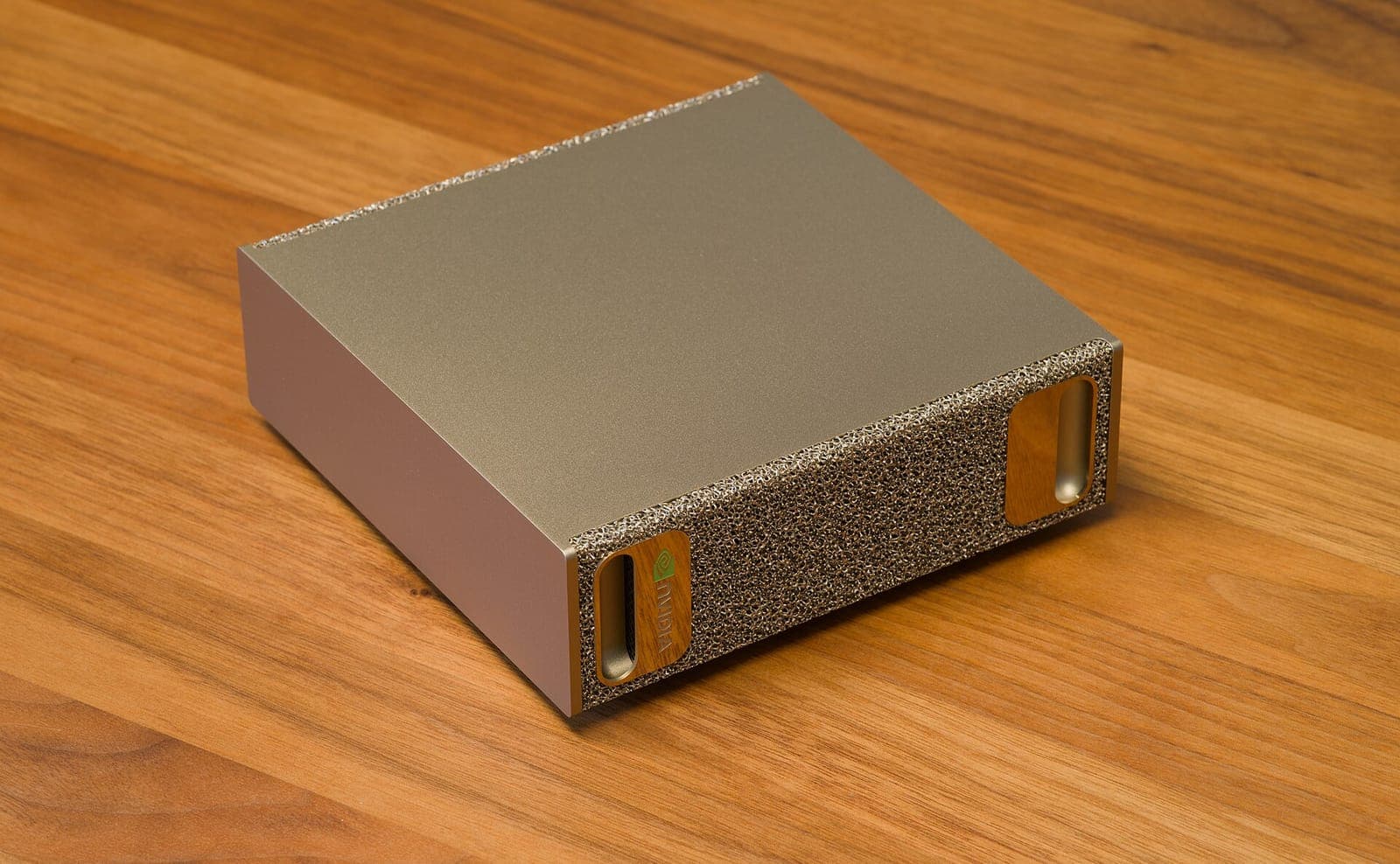 NVIDIA DGX Spark on a wooden desk, seen from above at an angle, showing the metal-foam front panel.